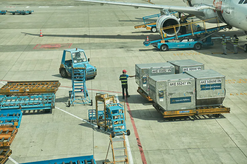Contenedores de carga aérea en la plataforma de un aeropuerto, junto al avión.